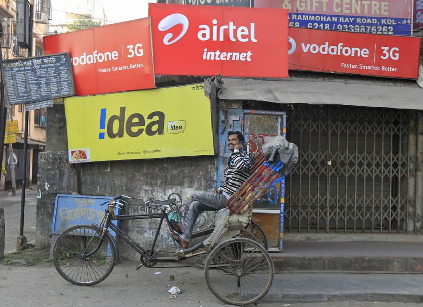 A rickshaw puller speaks on his mobile phone as he waits for customers in front of advertisement billboards belonging to telecom companies in Kolkata February 3, 2014. u00e2u20acu201d Reuters pic