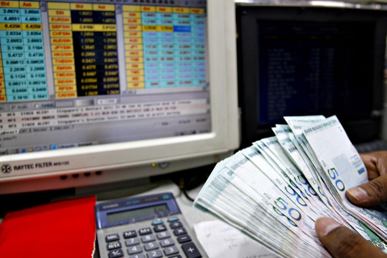 A money changer counts RM50 ringgit bills at a currency exchange in Kuala Lumpur April 7, 2006. u00e2u20acu201c AFP pic