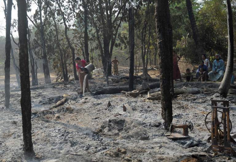A Muslim woman in Myanmar pours water over a smouldering fire of a burnt house after religious riots broke out in a village at Oakkan town, some 100km north of Yangon on May 1, 2013. u00e2u20acu201d AFP pic