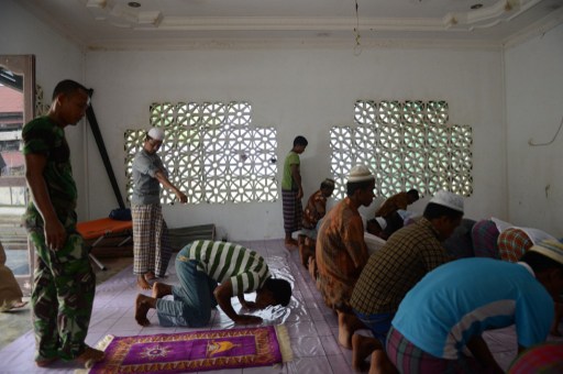 In this photograph taken on April 11, 2013, an Indonesian soldier (left) joins a group of Rohingya asylum-seekers from Myanmar in prayers in a mosque at the immigration detention centre in Lhokseumawe town of Aceh province. u00e2u20acu201d AFP pic