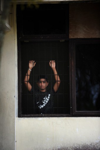 In this photograph taken on April 11, 2013, a Rohingya asylum-seeker from Myanmar looks through a window of the immigration detention centre in Lhokseumawe town of Aceh province. — AFP pic