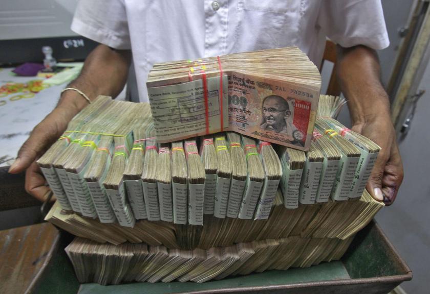 An employee poses with the bundles of Indian rupee notes inside a bank in Agartala, the capital of India's northeastern state of Tripura August 22, 2013. u00e2u20acu201c Reuters pic