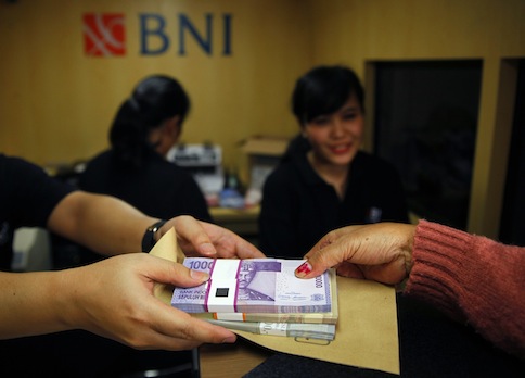 A woman holds Indonesian rupiah banknotes at a Bank Negara Indonesia (BNI) mobile bank in Jakarta July 15, 2013. u00e2u20acu201d Reuters pic