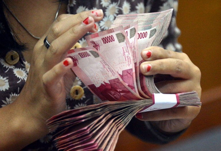 File photo of a woman counting Indonesia rupiah banknotes in Jakarta. u00e2u20acu201d AFP pic