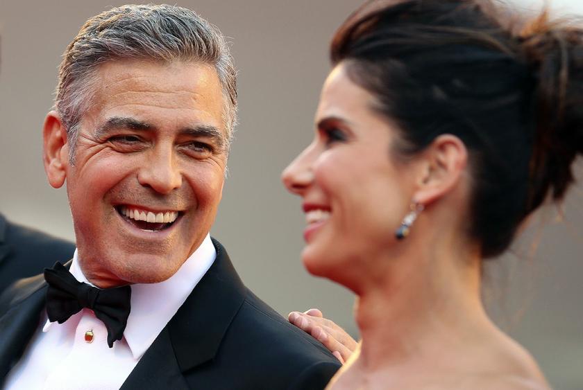 U.S. actor George Clooney (L) smiles next to actress Sandra Bullock as their arrive for the premiere of ,Gravity, at the 70th Venice Film Festival in Venice August 28, 2013