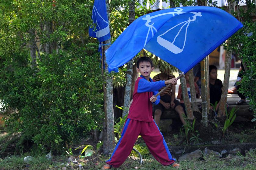 A boy waving a Barisan Nasional flag at the roadside near his home in Sungai Limau. u00e2u20acu201d Picture by K.E. Ooi