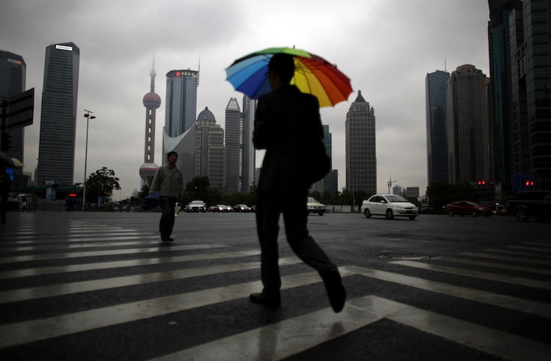 A businessman walks with an umbrella in the financial area of Pudong in Shanghai, May 30, 2013. u00e2u20acu201d Reuters pic