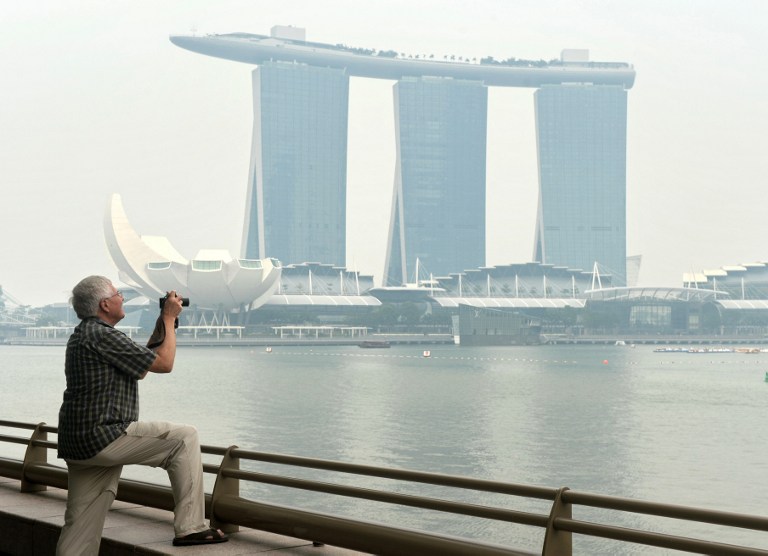 A man takes pictures in front of the Marina Bay Sands hotel as it is blanketed by haze in Singapore on June 17, 2013. u00e2u20acu201d AFP pic