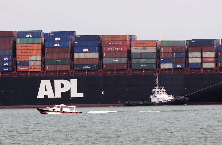 A pilot boat (right) guides a container vessel to the port in Singapore on May 23, 2013. u00e2u20acu201d AFP pic