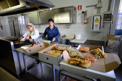 Carla Bellardinelli, (centre) volunteer of Caritas, controls the packs with food scraps from gourmet grocer Volpetti at the soup kitchen in the St. Benedict parish on May 28, 2013. — AFP pic
