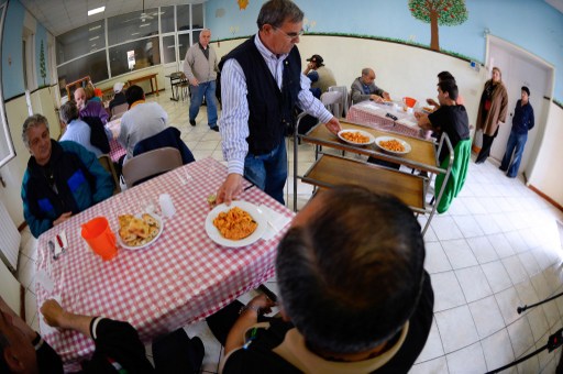 A volunteer of the Caritas Catholic charity serves meals at the soup kitchen of the St. Benedict parish in Rome on May 28, 2013. — AFP pic