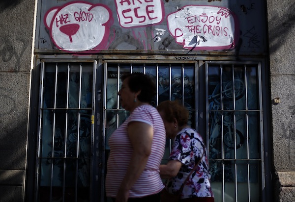Women walk past graffiti painted on the front of a closed motorbike shop in central Madrid August 26, 2013. The graffiti (left) reads, u00e2u20acu02dcBeam spendingu00e2u20acu2122. u00e2u20acu201d Reuters pic