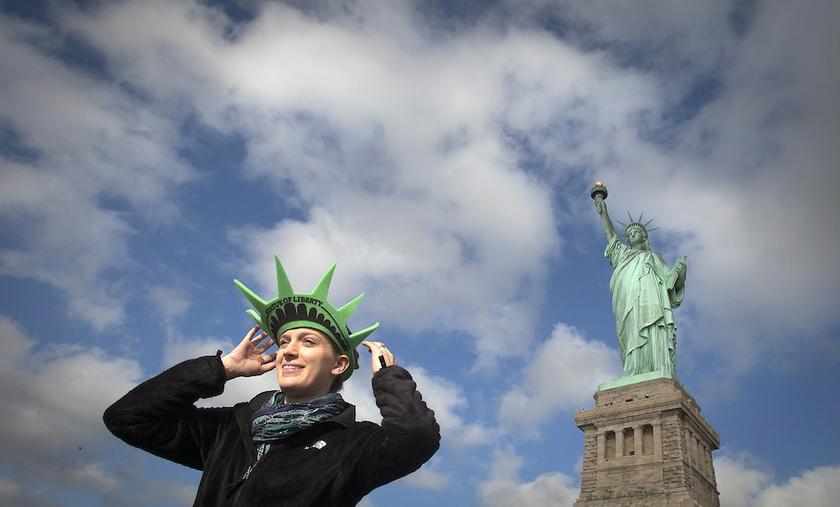 Bethany McNew, 24, from Tampa, adjusts her hat as she poses for a photo in front of the Statue of Liberty on Liberty Island in New York, October 13, 2013. She was on the first tour boat to visit Liberty Island since it was shuttered almost two weeks ago. 