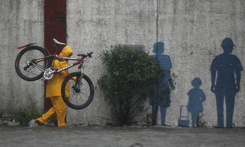A man carries his bicycle through a flooded street brought by the monsoon rain, intensified by tropical storm Trami, in Pasig city, metro Manila August 20, 2013. u00e2u20acu201c Reuters pic