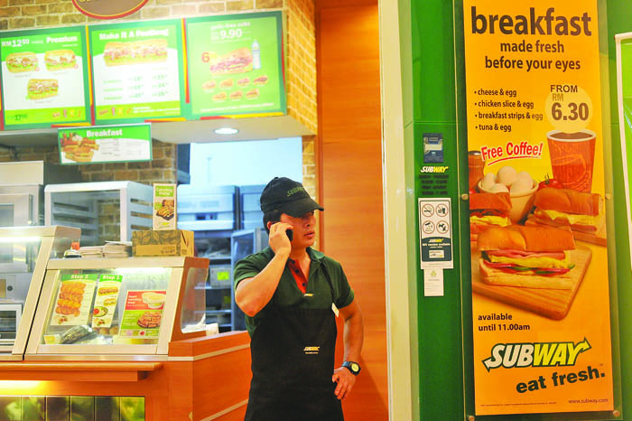 A foreign worker chats on the mobile phone at a Subway outlet in Petaling Jaya. An outlet manager in KL says foreigners are hardworking compared to locals. 