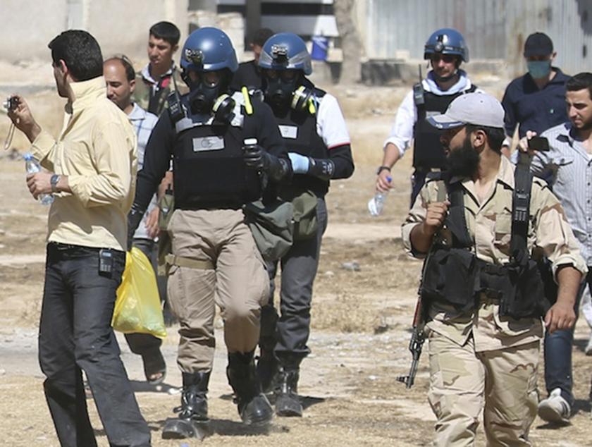 UN chemical weapons experts wearing gas masks carry samples collected from one of the sites of an alleged chemical weapons attack while escorted by Free Syrian Army fighters in the Ain Tarma neighbourhood of Damascus in this August 28, 2013 file photo.  u00e2