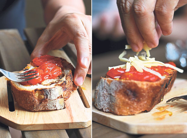 Spread the cooked or roasted cherry tomatoes over the slice of bread, mashing them into an even layer (left). Sprinkle a handful of grated Cheddar cheese over the mashed cherry tomato topping (right)