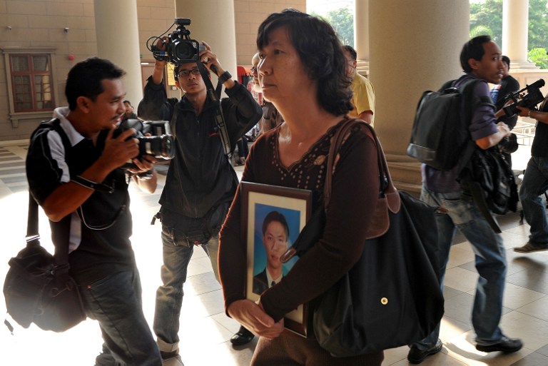 Teoh Shuw Hoi, the mother of late Malaysian political aide Teoh Beng Hock, walks towards the courtroom while holding a portrait of her son in Kuala Lumpur on February 14, 2011. u00e2u20acu201d AFP pic