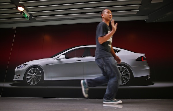 A man gestures as he walks past a billboard-sized photo of the Tesla Model S car, outside the boarded-up Teslau00e2u20acu2122s first China flagship showroom in Beijing August 23, 2013. u00e2u20acu201d Reuters pic