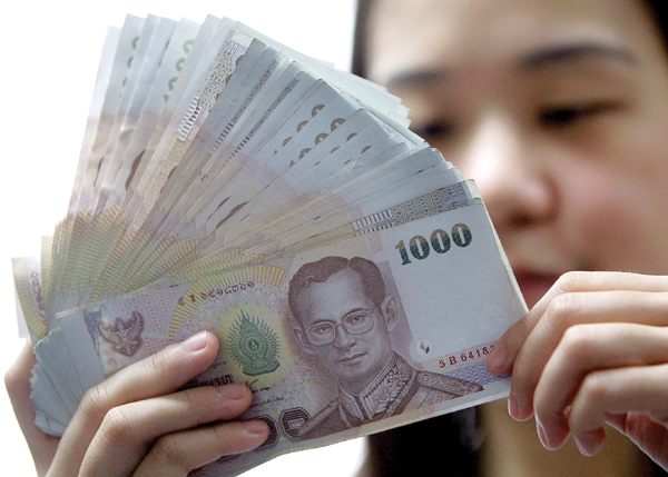 File photo of a bank cashier counting Thai baht notes in a bank in Bangkok. u00e2u20acu201c AFP pic