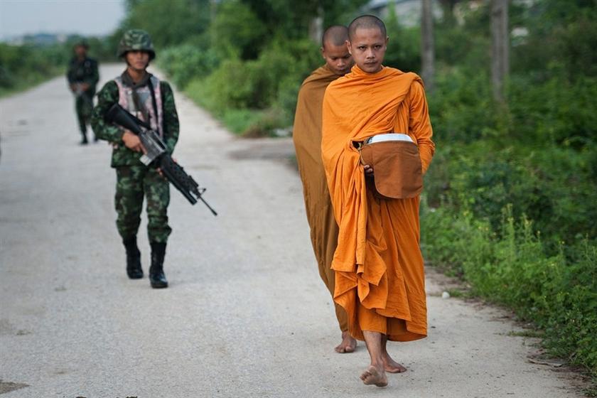 Thai soldiers (left) providing security to Buddhist monks during their daily morning alms collection in the village of Leamnok on the outskirts of Thailand's southern province of Pattani. u00e2u20acu201d AFP pic