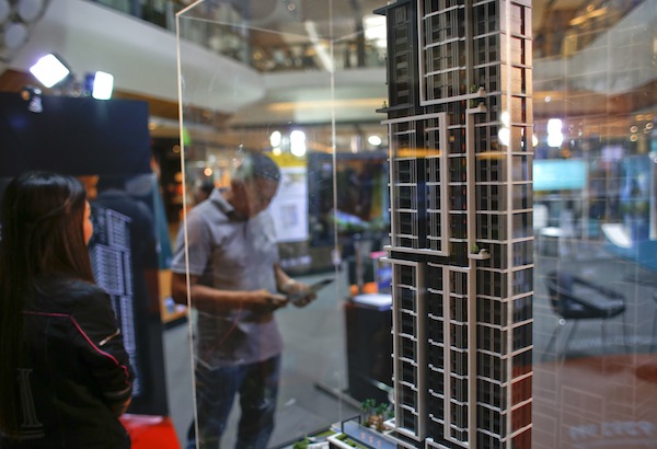 A visitor stands next to a model of a condominium at an exhibition booth in a department store in Bangkok August 4, 2013. u00e2u20acu201d Reuters pic