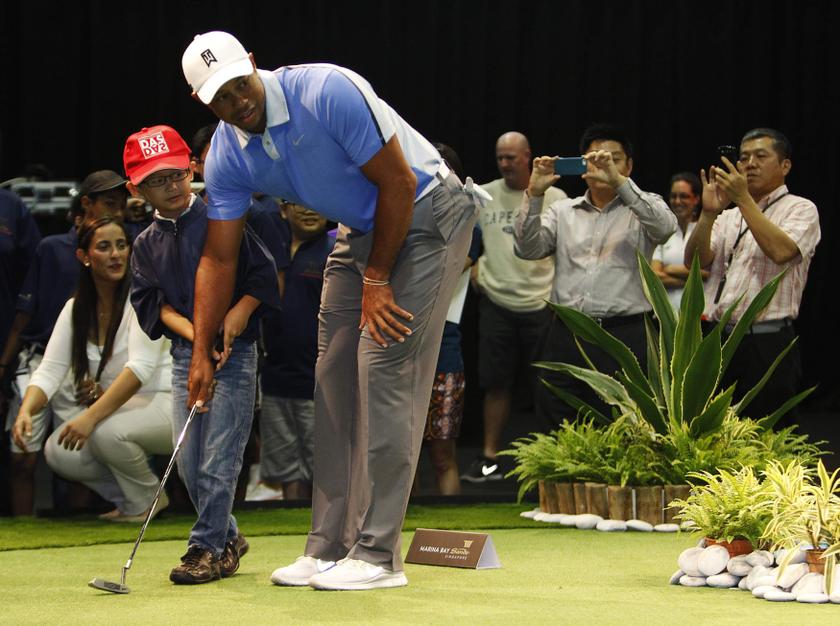 US golfer Tiger Woods guides a boy as he putts on a hole during an event to meet with young athletes in Singapore November 1, 2013. u00e2u20acu201d Reuters pic
