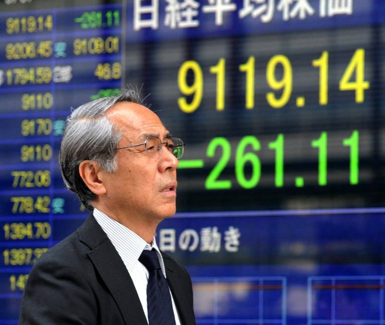A businessman passes before a share prices board in Tokyo on May 7, 2012. u00e2u20acu201c AFP pic