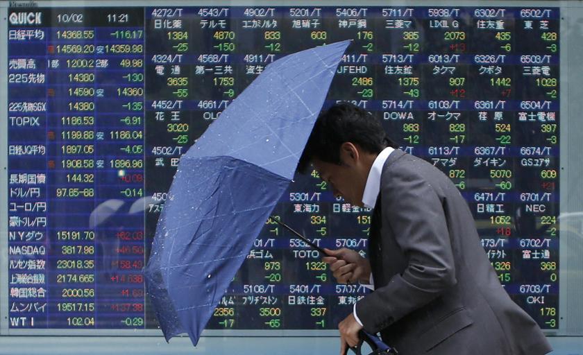 A man walks against strong wind and rain in front of a stock quotation board outside a brokerage in Tokyo October 2, 2013. u00e2u20acu201d Reuters pic