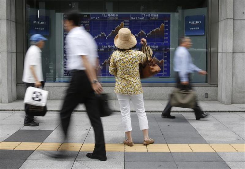 Pedestrians walk past a stock quotation board displaying graphs of various stock indexes outside a brokerage, in Tokyo June 14, 2013. u00e2u20acu201d Reuters pic