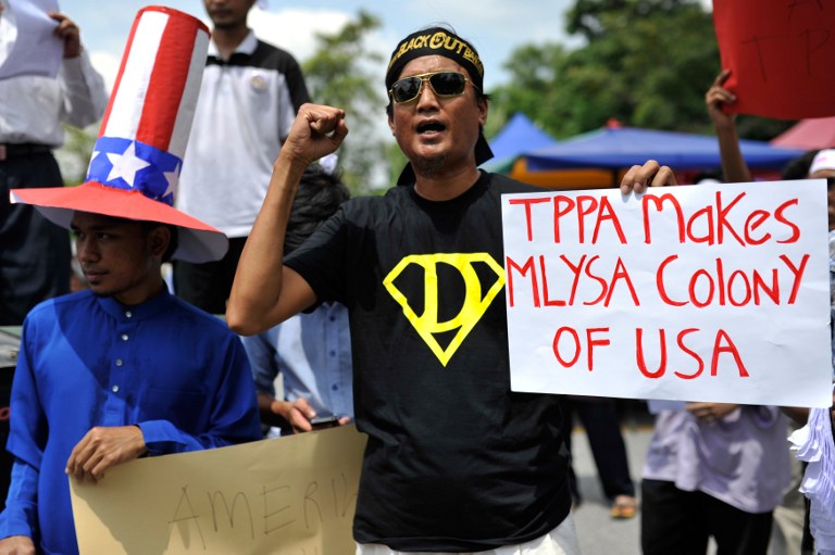 A demonstrator holds up a placard during a protest against Malaysia's participation in rule-making negotiations for the Trans-Pacific Partnership agreement  in Kuala Lumpur on July 19, 2013. u00e2u20acu201c AFP pic