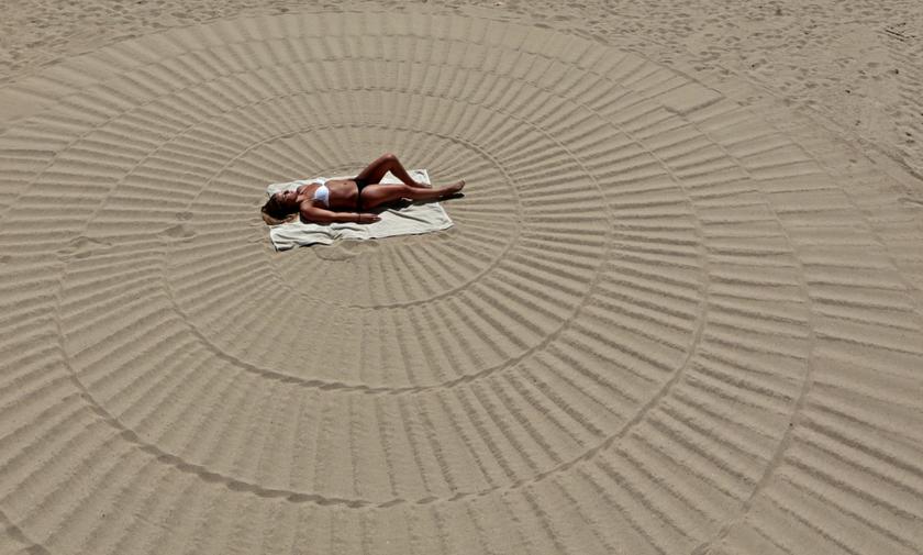 Australian tourist Caitlin takes in the sun on a beach of the Croisette during a hot summer day in Cannes July 31, 2013