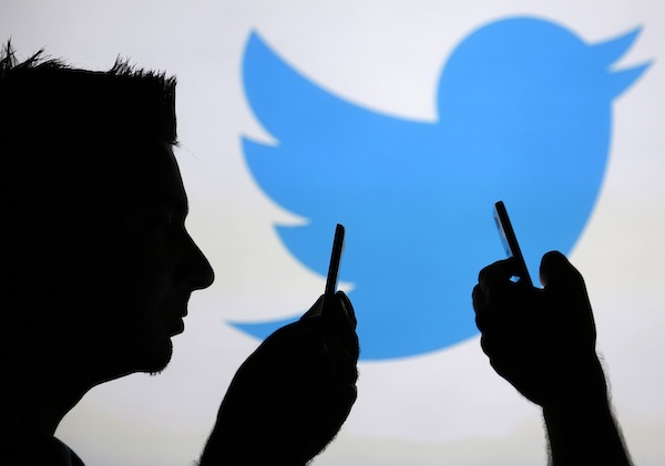 Men are silhouetted against a video screen with an Twitter logo in this photo illustration taken in the central Bosnian town of Zenica, August 14, 2013. u00e2u20acu201d Reuters pic