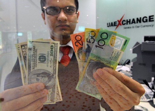 Money changer Tirth Acharya of India displays a selection of US dollars (left) and Australian polymer notes as the local currency reached parity in Sydney on May 14, 2012. u00e2u20acu201d AFP pic
