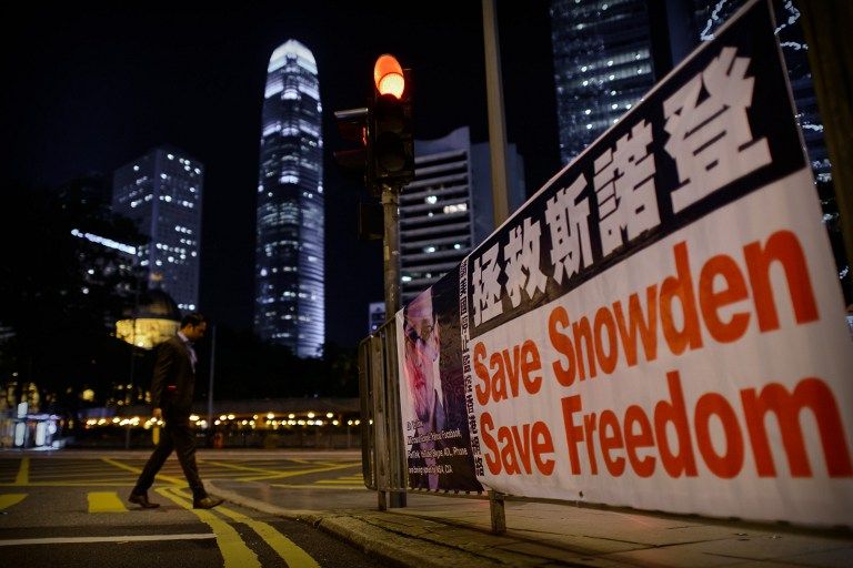 CHINA, HONG KONG : A man crosses a street next to banner displayed in support of former US spy Edward Snowden in Hong Kong on late June 17, 2013. Snowden's presence in Hong Kong is shining a global spotlight on the city, where relations with Beijing is te