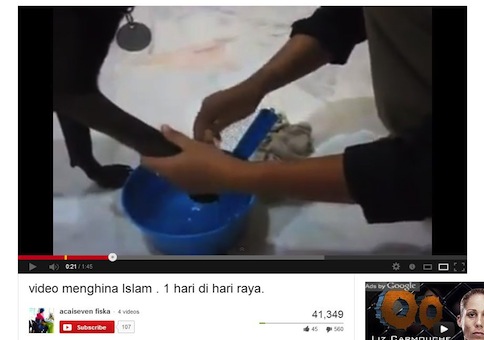 Screen capture of a YouTube video shows a Muslim woman cleaning the paws of her pet dog.