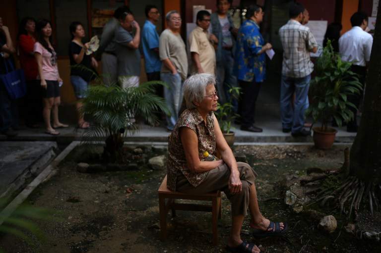 A woman sits as others queue to cast their votes during the 13th general election in Kuala Lumpur on May 5, 2013. u00e2u20acu201d AFP pic