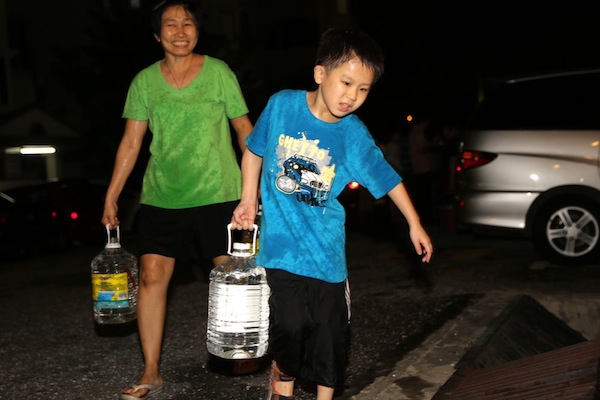 A boy helps his mother carry water home, as supplied by a tanker, following a water cut in Puchong, August 31, 2013. u00e2u20acu201d Picture by Choo Choy May