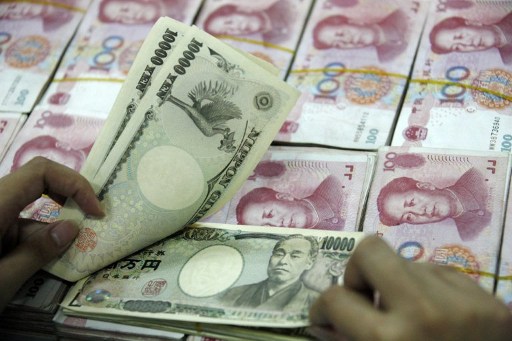 A Chinese bank clerk shows off 10,000 Japanese Yen notes among the stacks of 100 yuan notes, at a bank in Huaibei, east China's Anhui province on May 29, 2012. u00e2u20acu201d AFP pic
