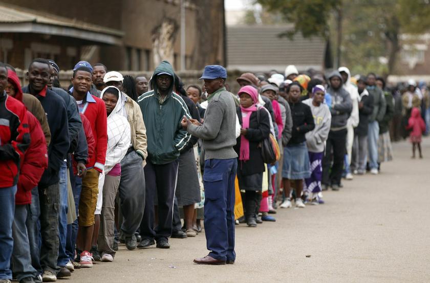 A police officer keeps watch as Zimbabweans wait to cast their vote in Mbare township outside Harare July 31, 2013
